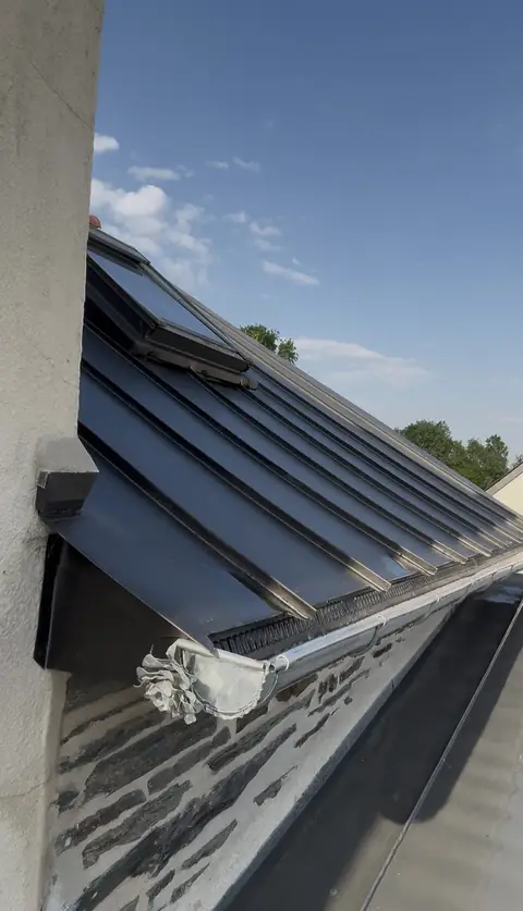 Égout d'une couverture zinc noir à joint debout : bande d'égout ventilée, gouttière demi-ronde neuve et naissance ornée d'une rose en zinc