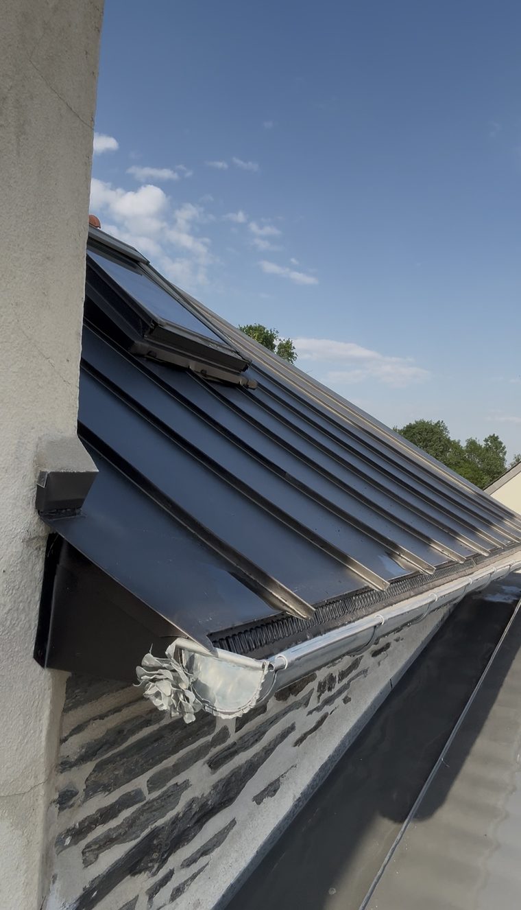 Égout d'une couverture zinc noir à joint debout : bande d'égout ventilée, gouttière demi-ronde neuve et naissance ornée de la rose en zinc