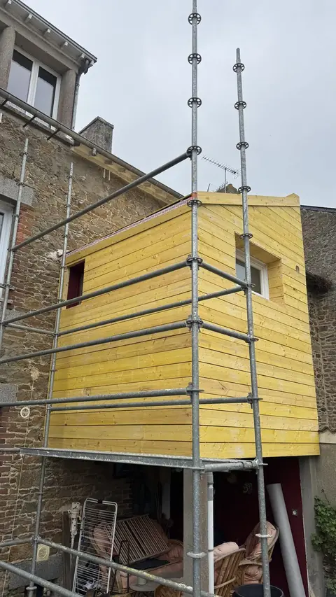 Extension à ossature bois brute adossée à une maison en pierre, voligeage posé, avant l'habillage en zinc