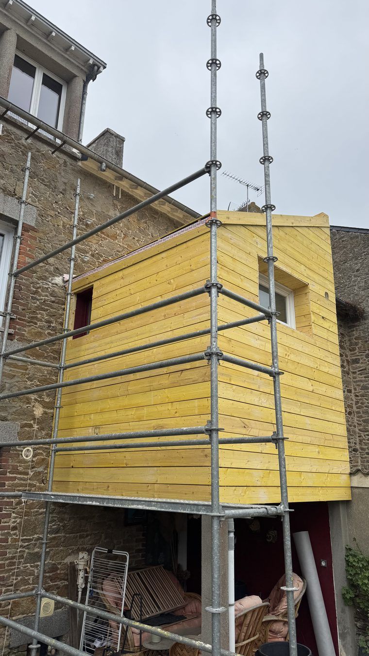 Extension à ossature bois brute adossée à une maison en pierre, voligeage posé, avant l'habillage en zinc