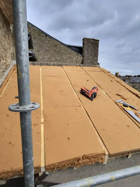 Panneaux d'isolant en fibre de bois posés en sarking sur la toiture de l'extension, cloueur pneumatique posé dessus