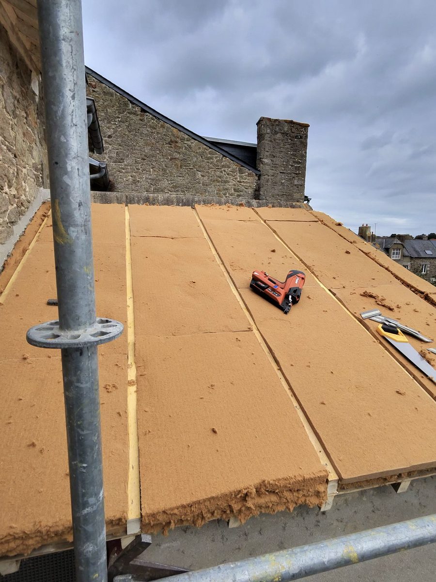 Panneaux d'isolant en fibre de bois posés en sarking sur la toiture de l'extension, cloueur pneumatique posé dessus