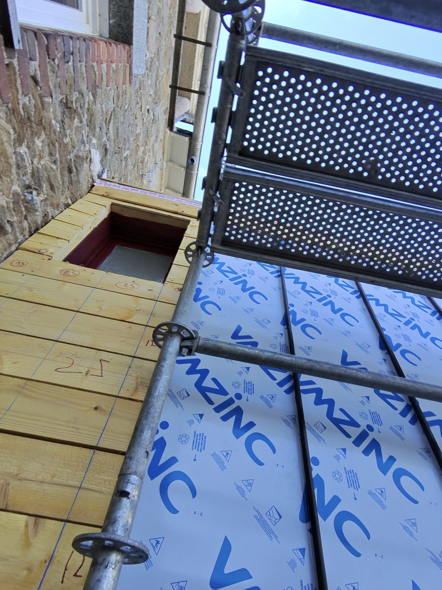 Feuilles de zinc VMZINC sous film de protection posées contre le voligeage neuf, cotes tracées au crayon rouge sur les planches