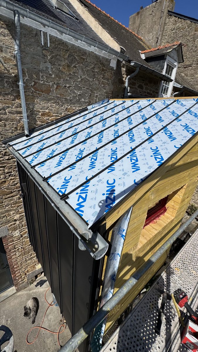 Toiture en zinc à joint debout vue de l'échafaudage, feuilles sous film de protection, gouttière et naissance déjà en place