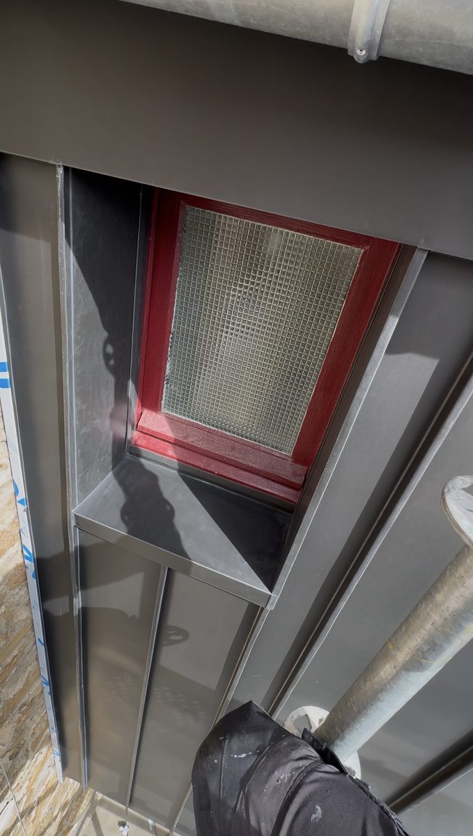 Habillage en zinc de l'encadrement d'une fenêtre : ébrasements, linteau et appui façonnés dans le même zinc anthracite
