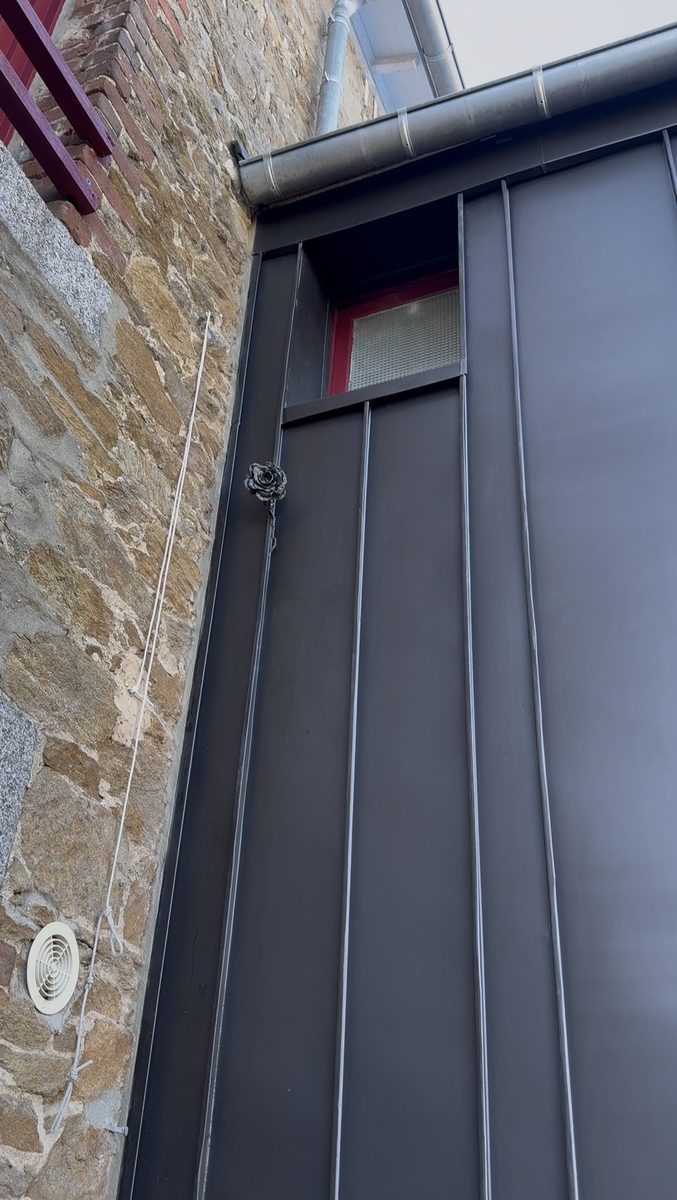 Rose en zinc façonnée à la main fixée sur la façade à joint debout, signature des Couvreurs Malouins