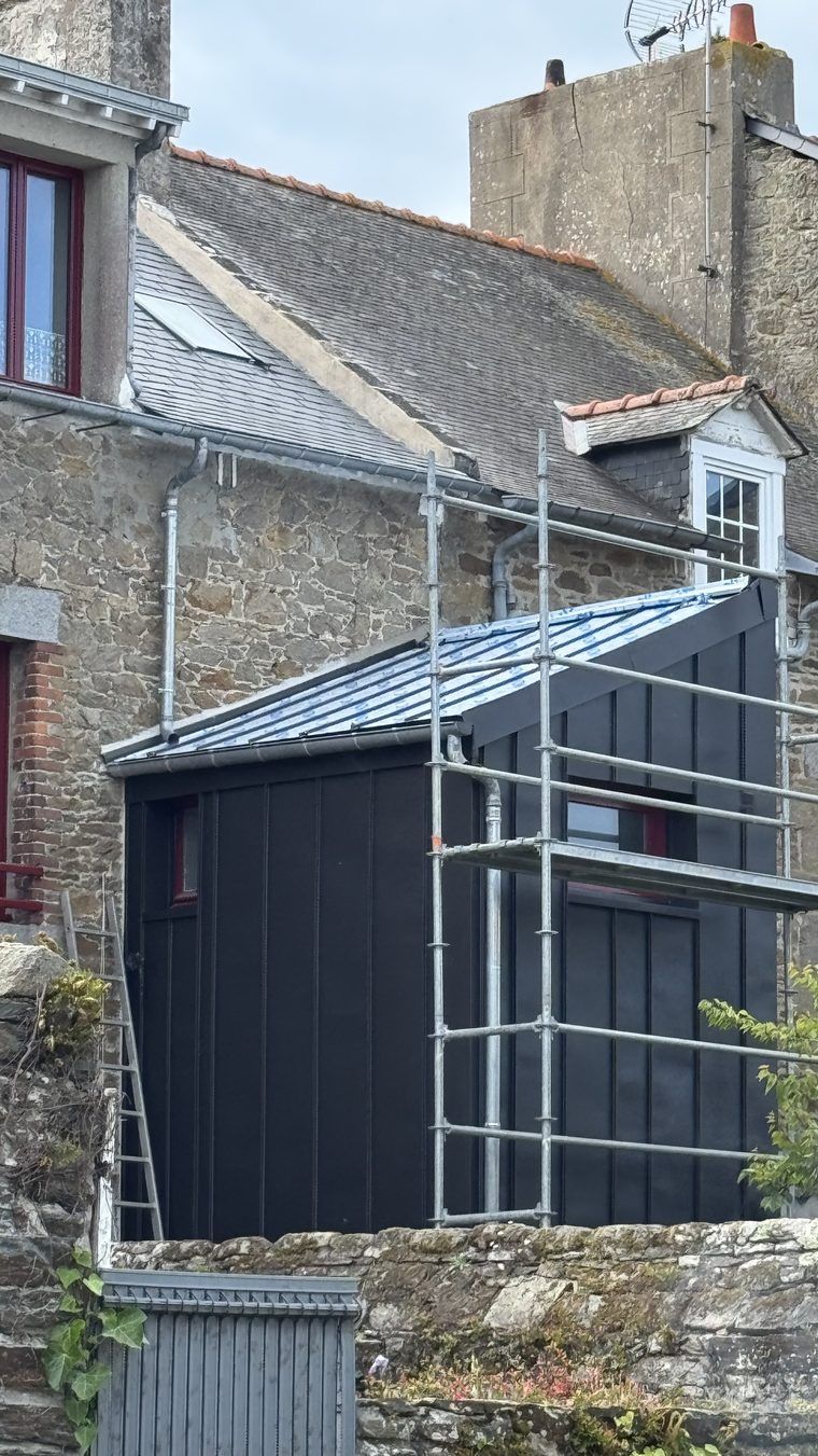 Pose du zinc anthracite à joint debout en cours sur l'extension : toiture sous film de protection, bardage vertical déjà serti