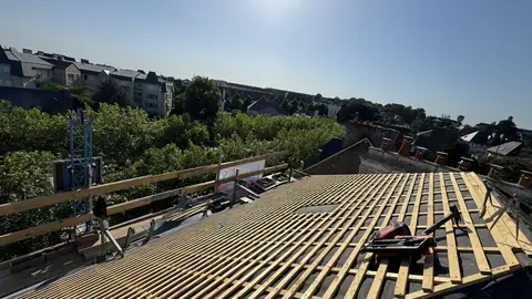 Écran de sous-toiture et liteaunage neufs sur toute la toiture, monte-matériaux en place, vue sur les toits de Saint-Malo
