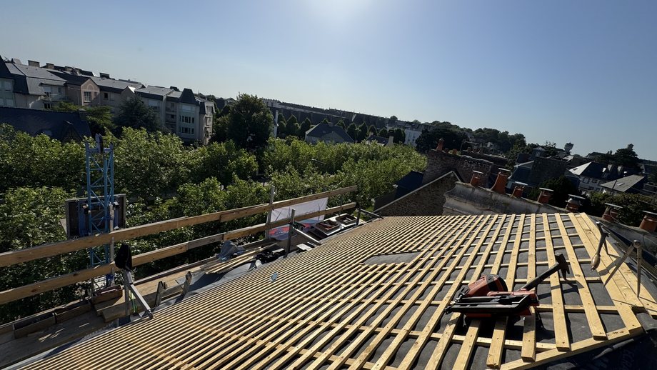 Écran de sous-toiture et liteaunage neufs sur toute la toiture, monte-matériaux en place, vue sur les toits de Saint-Malo