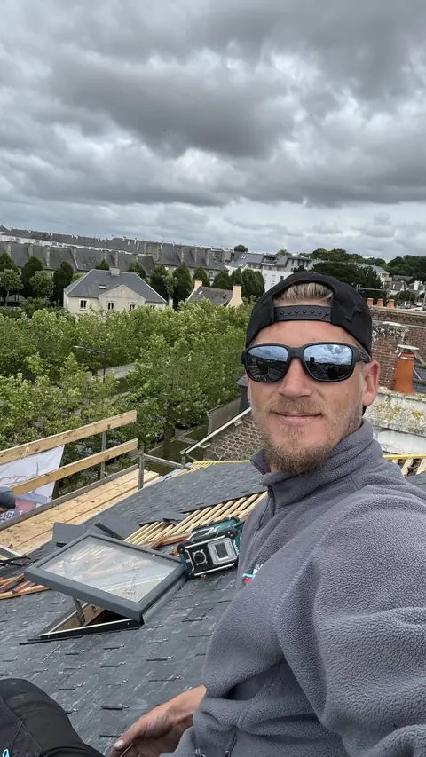 Pose d'une fenêtre de toit VELUX dans la couverture ardoise neuve, châssis en cours d'intégration