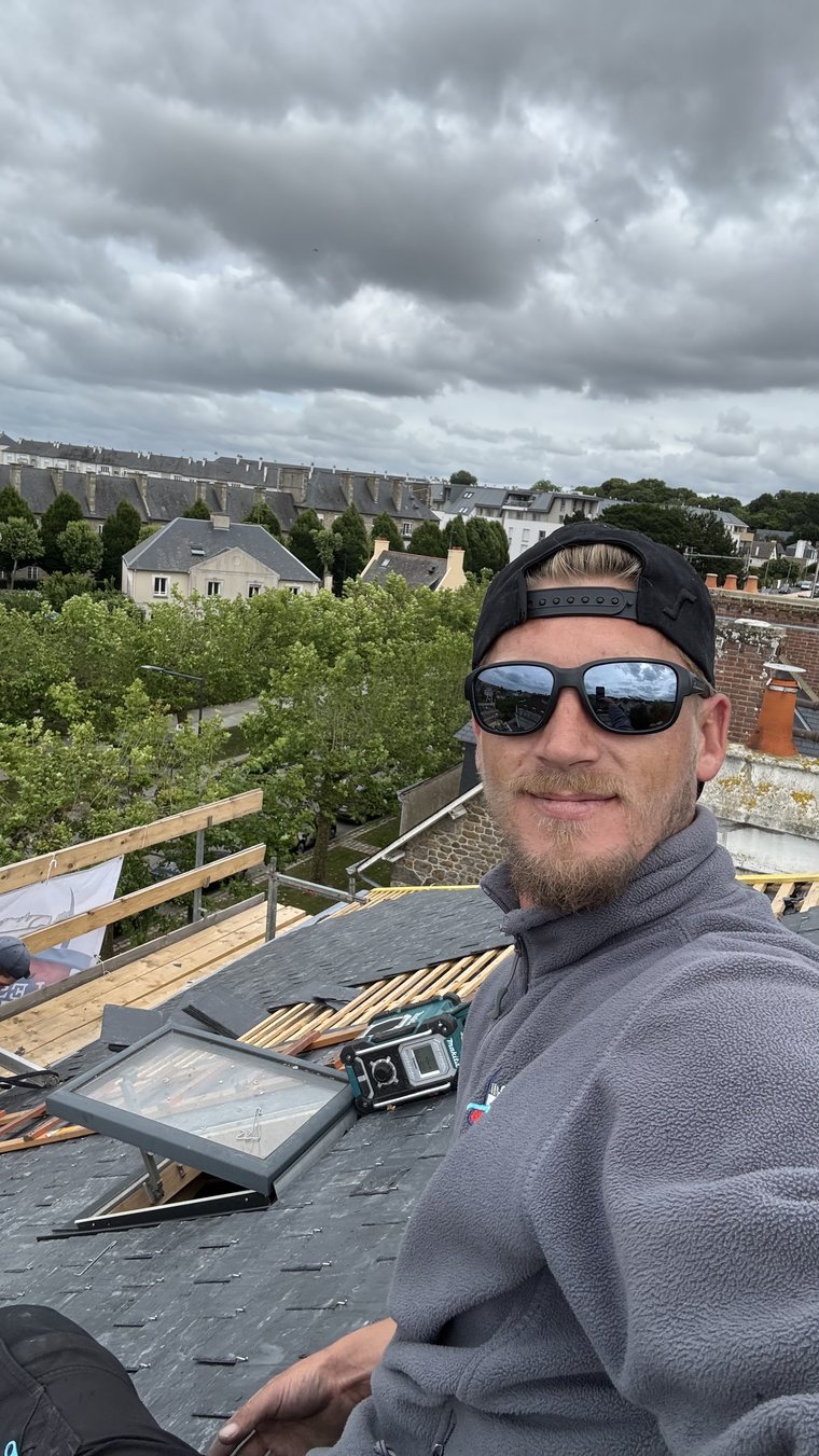 Pose d'une fenêtre de toit VELUX dans la couverture ardoise neuve, châssis en cours d'intégration