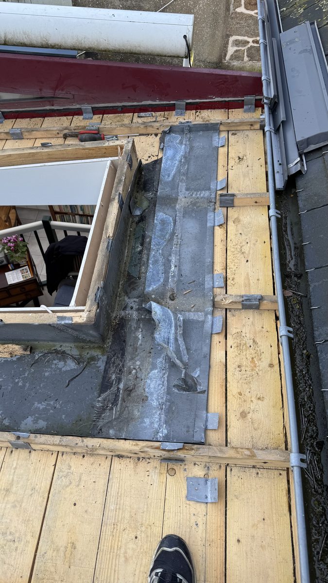 Dépose du zinc ancien en cours, voligeage bois neuf posé autour de la trémie de la fenêtre de toit, chéneau et couvertine visibles