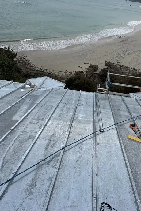 Après : le même terrasson en zinc naturel neuf à tasseaux, en cours de pose, face à la plage de Saint-Lunaire