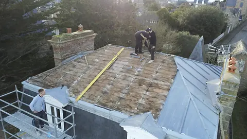 Vue au drone pendant la dépose : ancien zinc retiré, voligeage en bois à nu, couvreurs sur le terrasson et sur l'échafaudage