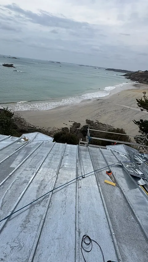 Terrasson en zinc neuf à tasseaux en cours de pose, vue plongeante sur la plage et la mer à Saint-Lunaire