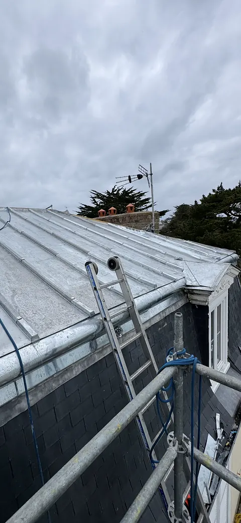 Échelle posée sur le terrasson en zinc neuf depuis l'échafaudage, membron en zinc et brisis en ardoise, ciel couvert
